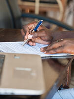 A Ugandan man writing on a form. Image: Kalungi Kabuye / UNU-WIDER
